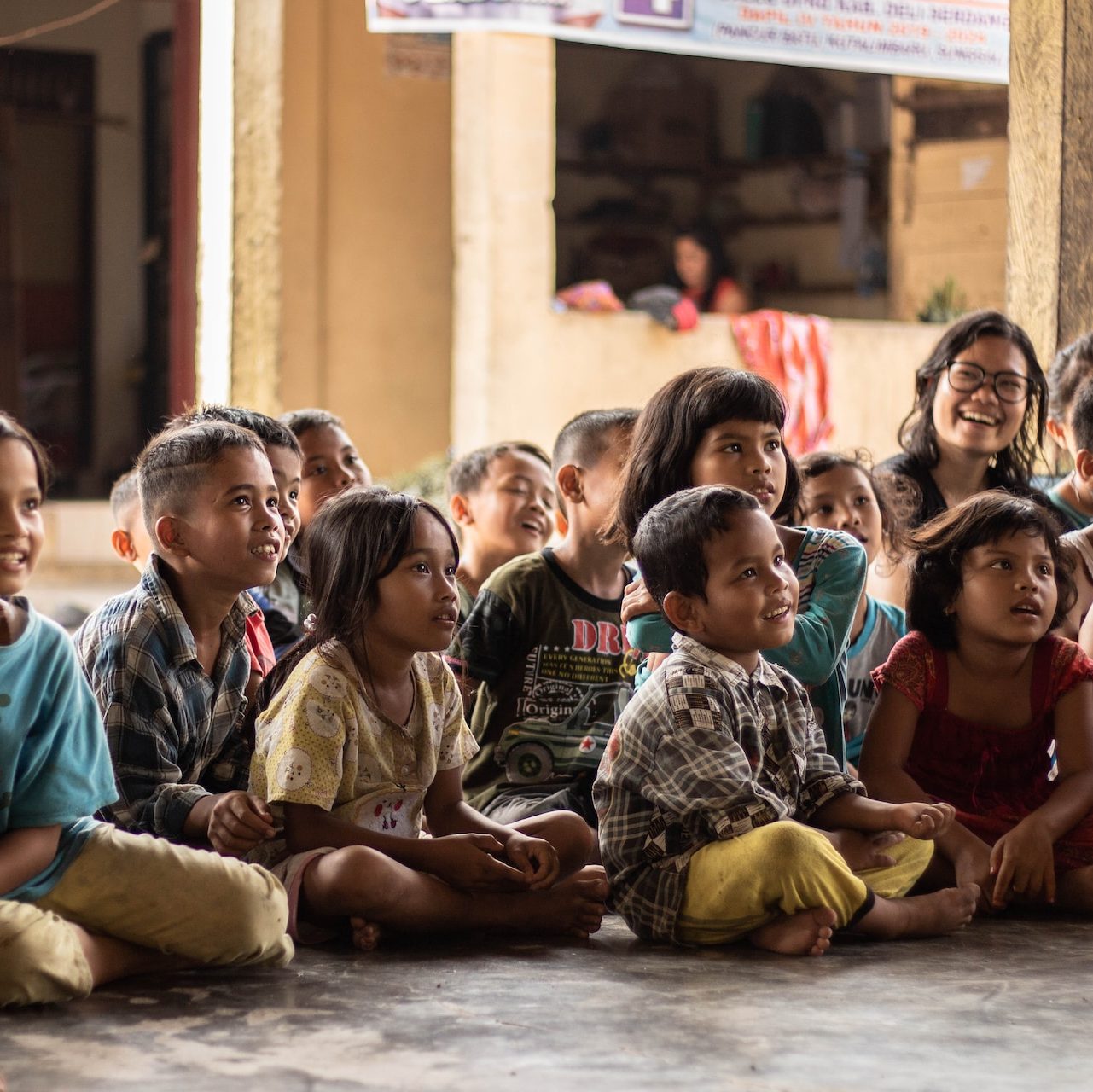 Schulkinder sitzend, verkörpern "Help 4 Life Global e.V."'s Einsatz für weltweite Bildung.